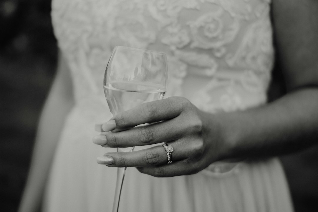 Dettaglio editoriale di una sposa con champagne e anello